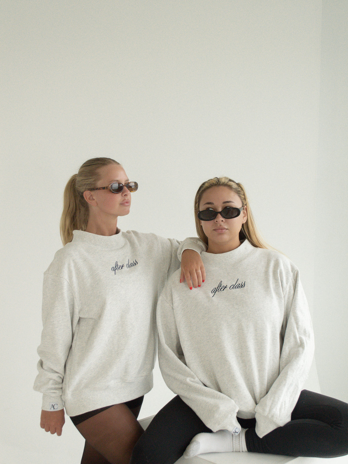 Two models wearing the heather-grey After Class mockneck sweatshirt with sunglasses